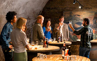 Guests participating in a beer tasting session in a rustic cellar setting.