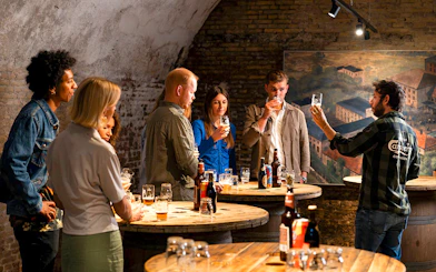 Guests participating in a beer tasting session in a rustic cellar setting.