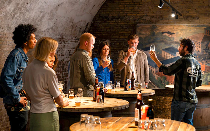 Guests participating in a beer tasting session in a rustic cellar setting.