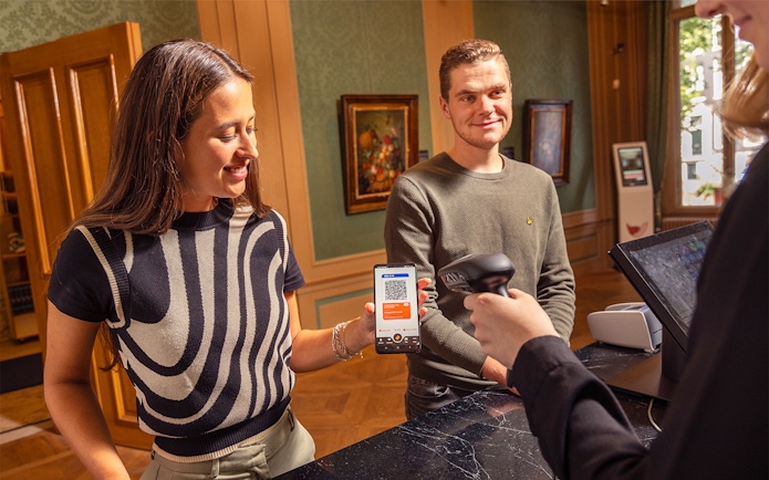 Visitors using I amsterdam City Card at museum entrance.