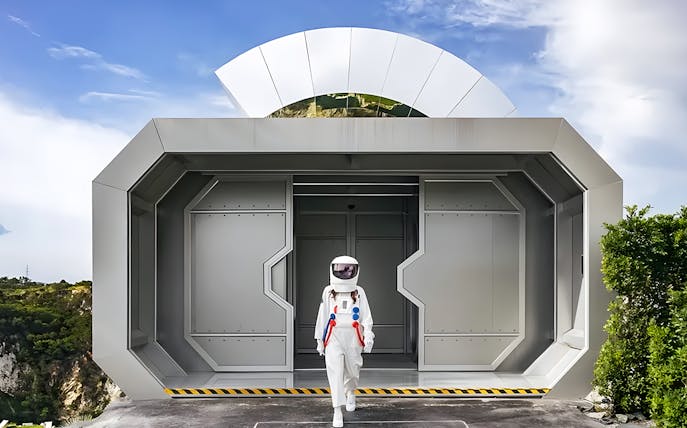 Astronaut exiting futuristic building at LOF LAND attraction.