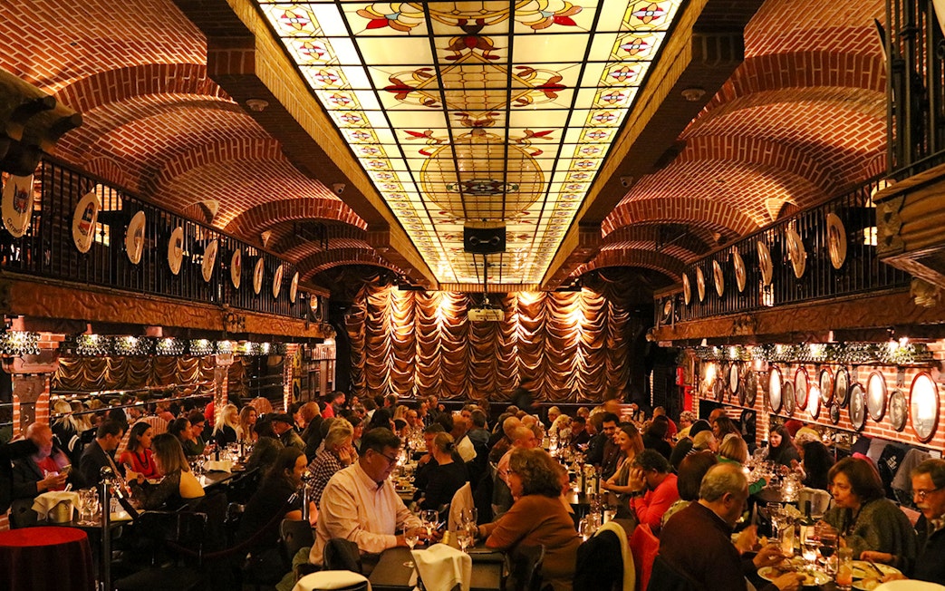 Guests dining at Piazzolla Tango Show venue with ornate ceiling and stage in Buenos Aires.