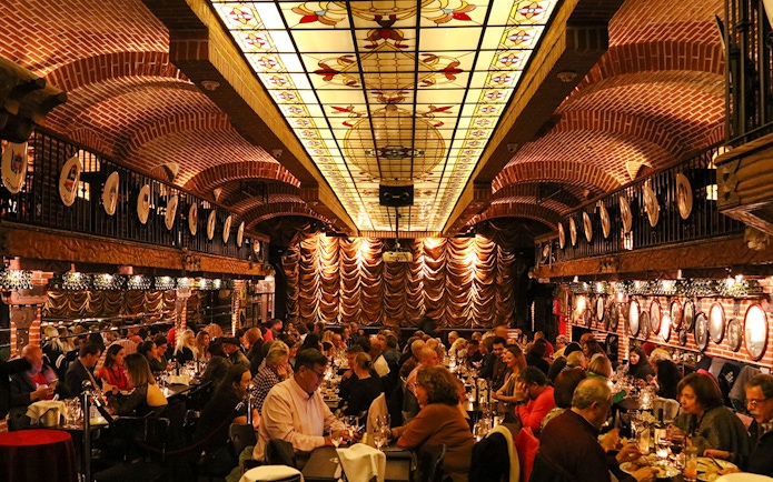 Guests dining at Piazzolla Tango Show venue with ornate ceiling and stage in Buenos Aires.
