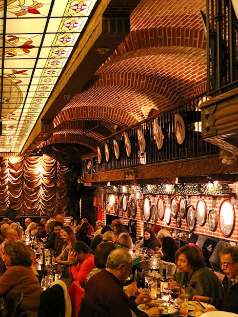 Guests dining at Piazzolla Tango Show venue with ornate ceiling and stage in Buenos Aires.