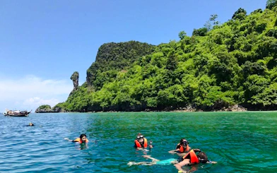 Snorkelers exploring clear waters near lush islands on Krabi's 7 Islands Sunset Tour.