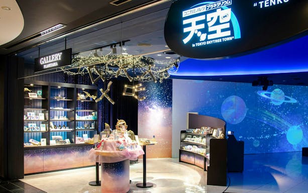 Shop interior at Konica Minolta Planetarium Tenku, Tokyo Skytree, featuring space-themed merchandise.