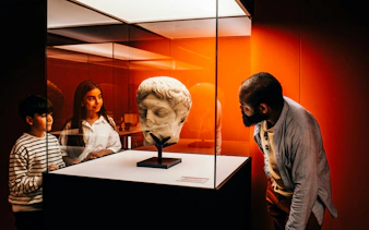 Visitors observing a Roman sculpture at IDEAL Barcelona's Pompeia experience.