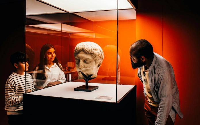 Visitors observing a Roman sculpture at IDEAL Barcelona's Pompeia experience.
