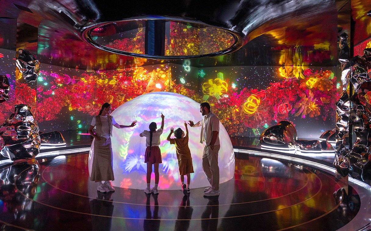Family interacting with colorful digital art at The Source in AYA Universe.
