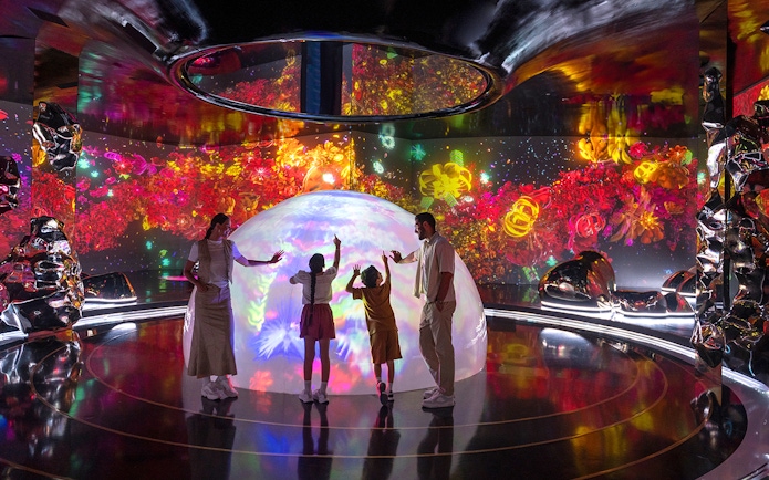 Family interacting with colorful digital art at The Source in AYA Universe.