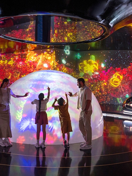 Family interacting with colorful digital art at The Source in AYA Universe.