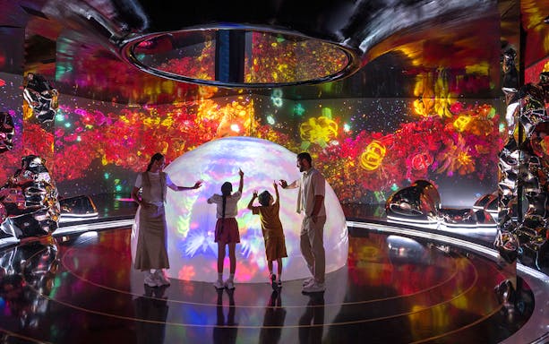Family interacting with colorful digital art at The Source in AYA Universe.