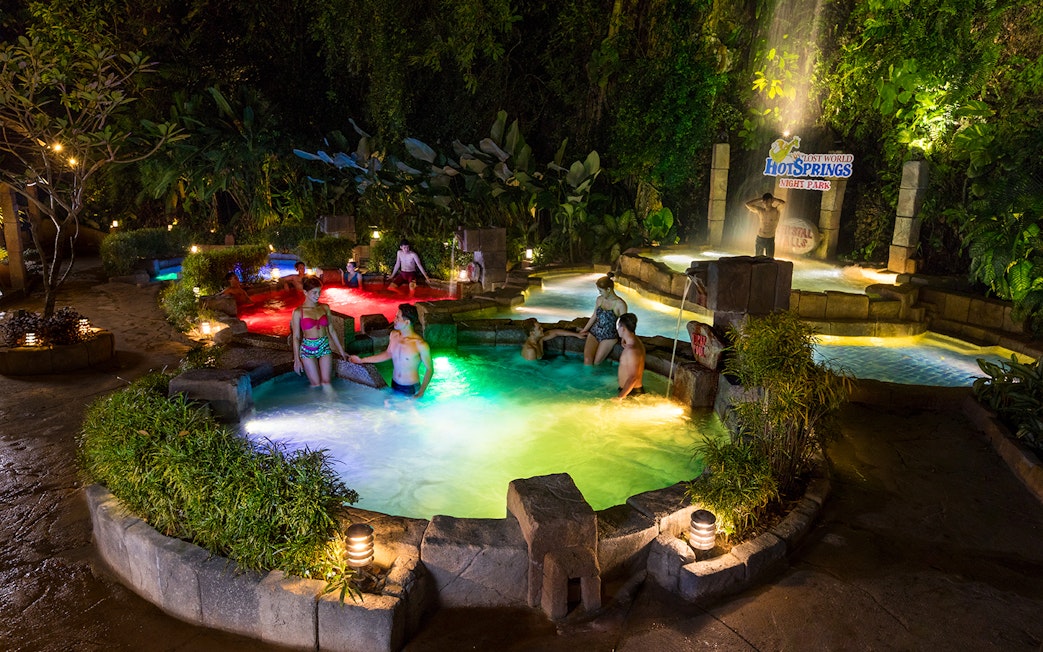 Visitors enjoying hot springs at Sunway Lost World of Tambun, Malaysia, surrounded by lush greenery.