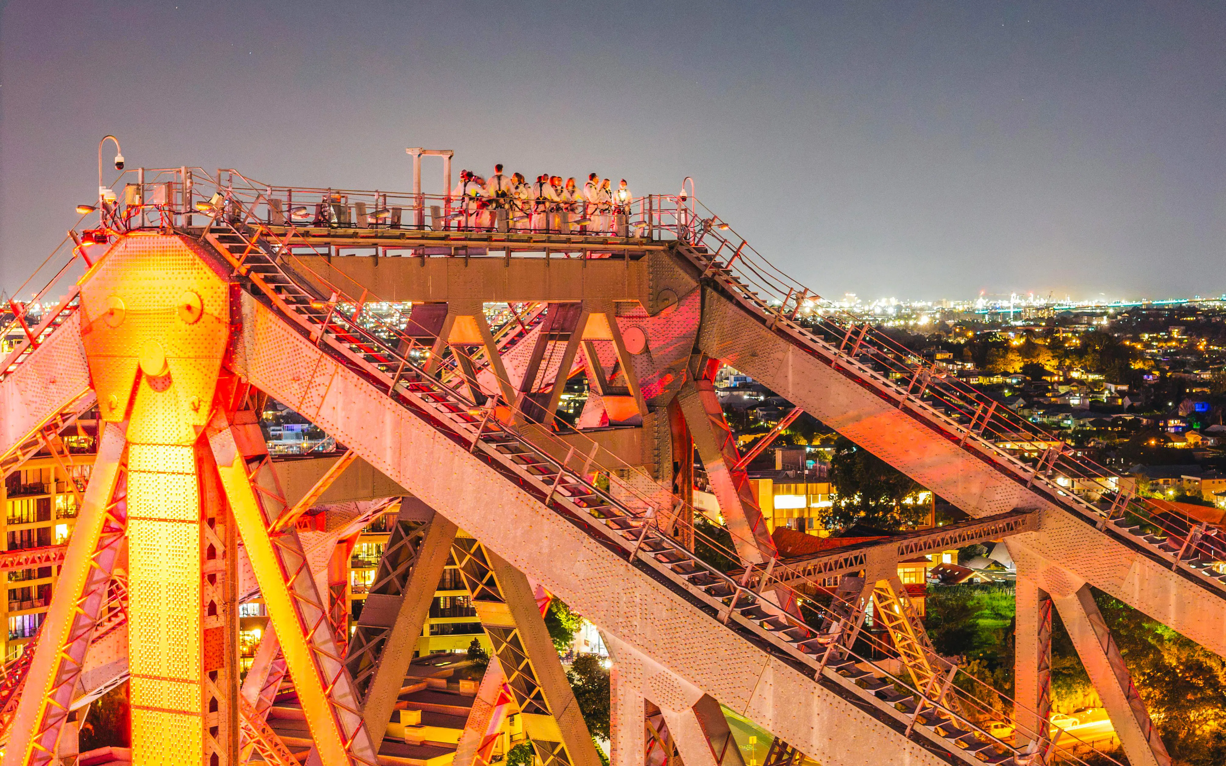 Climbers on Story Bridge at night with city lights in Brisbane, Australia.