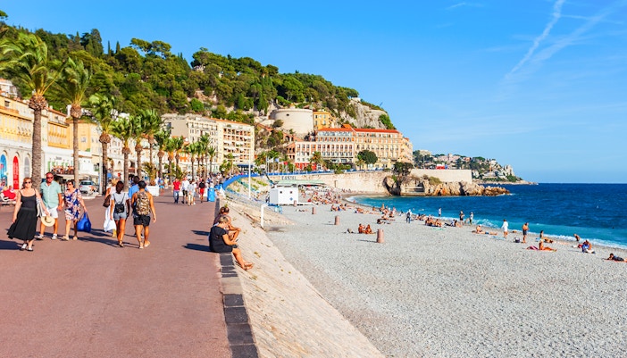 Promenade des Anglais in Nice with beachgoers and colorful buildings along the coast.