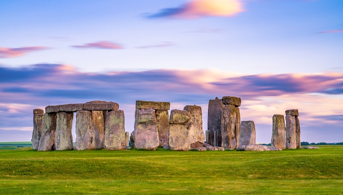 Stonehenge stone circle at sunset in England with colorful sky.