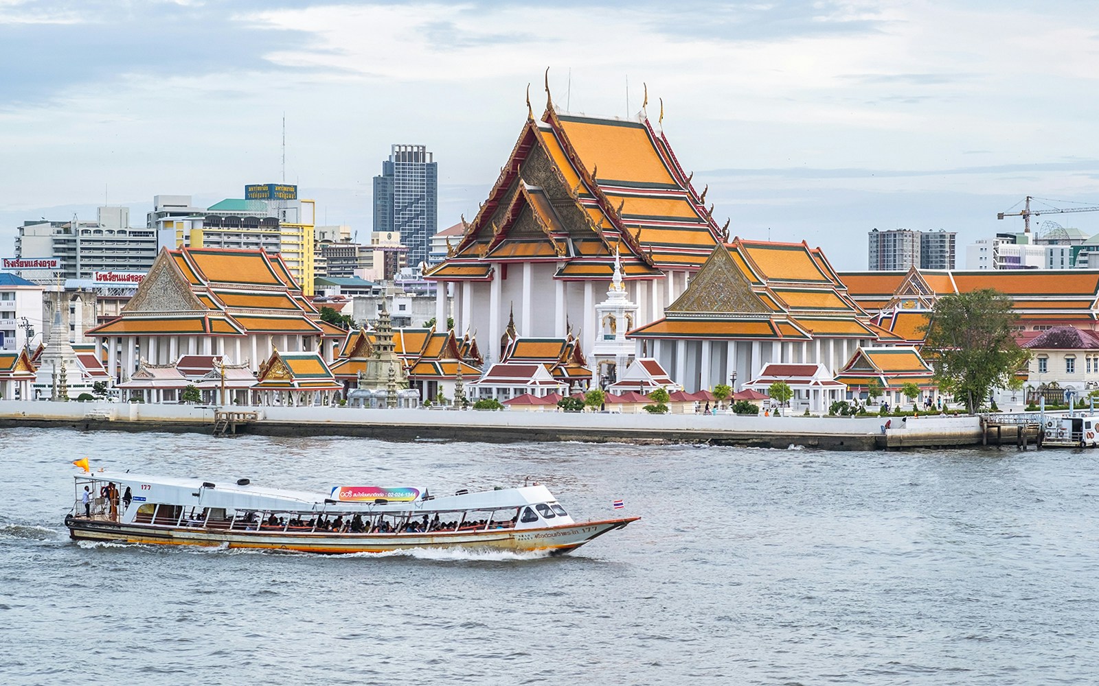 Wat Kanlaya temple with a boat on the Chao Phraya River in Bangkok.
