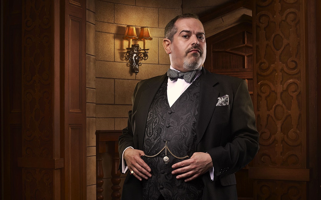 Man in formal attire standing in a vintage theater setting for The Mousetrap.
