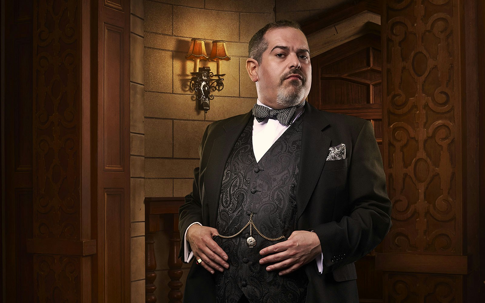 Man in formal attire standing in a vintage theater setting for The Mousetrap.
