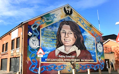 Belfast mural of Bobby Sands on a brick building, part of a guided political taxi tour.