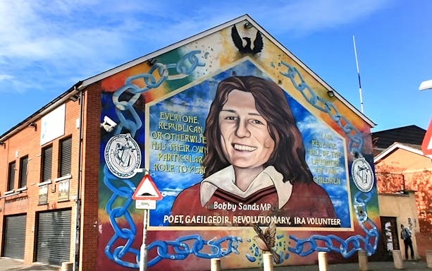 Belfast mural of Bobby Sands on a brick building, part of a guided political taxi tour.