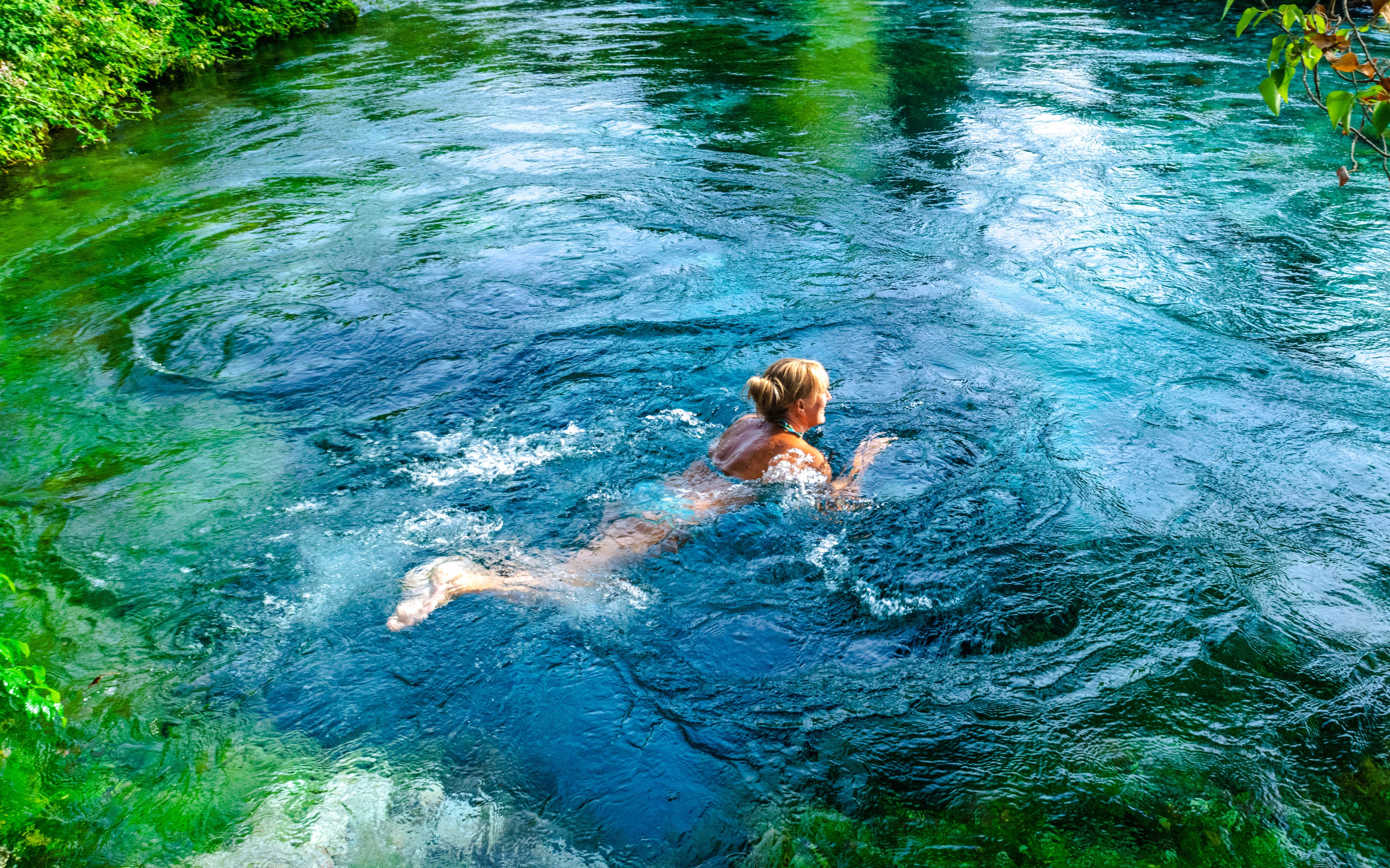 Person swimming in the clear waters of Blue Eye, Albania.