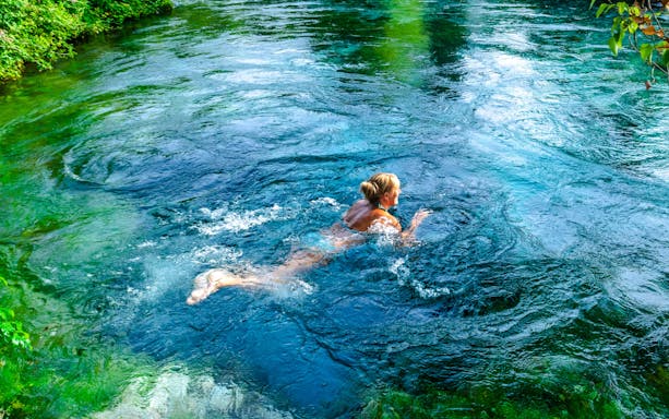 Person swimming in the clear waters of Blue Eye, Albania.