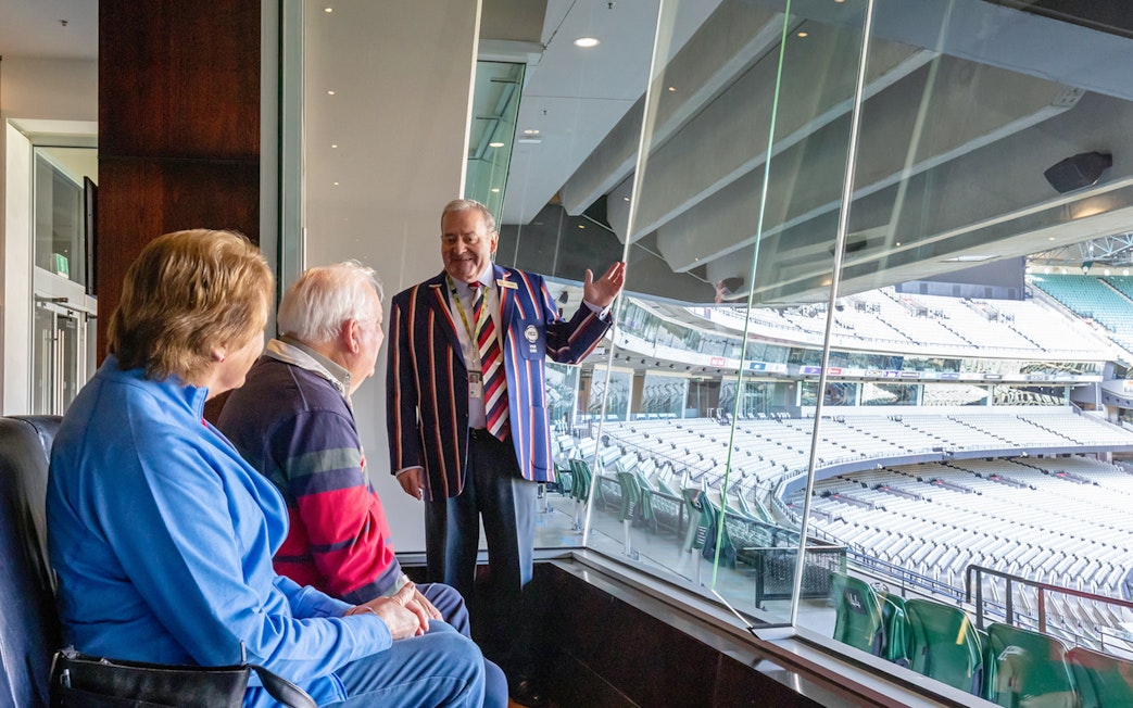 Tour guide explaining Melbourne Cricket Ground to visitors during guided sports walk.