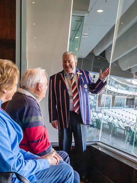 Tour guide explaining Melbourne Cricket Ground to visitors during guided sports walk.