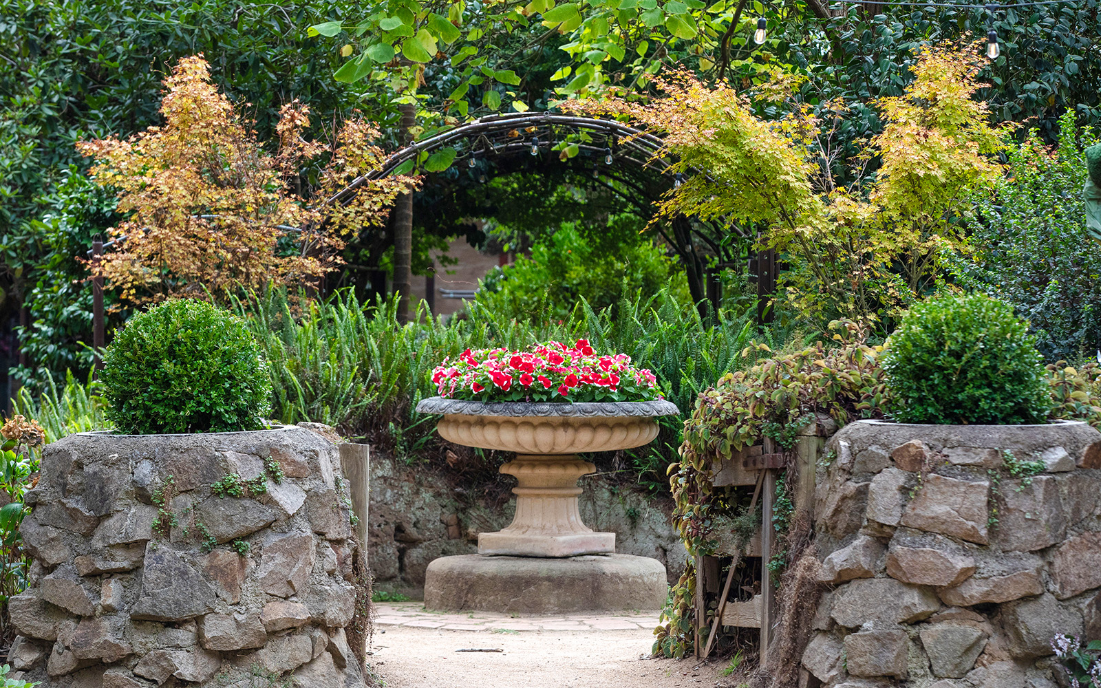 Stone pathway leading to a flower urn in Aschombe Maze & Lavender Gardens.