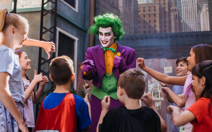 Tourists interact with Joker character at Movie World theme park.