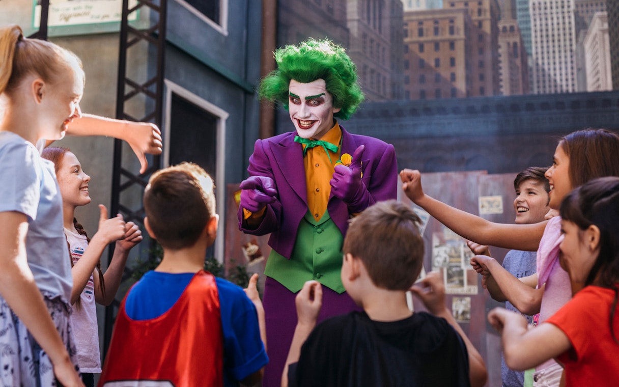 Tourists interact with Joker character at Movie World theme park.