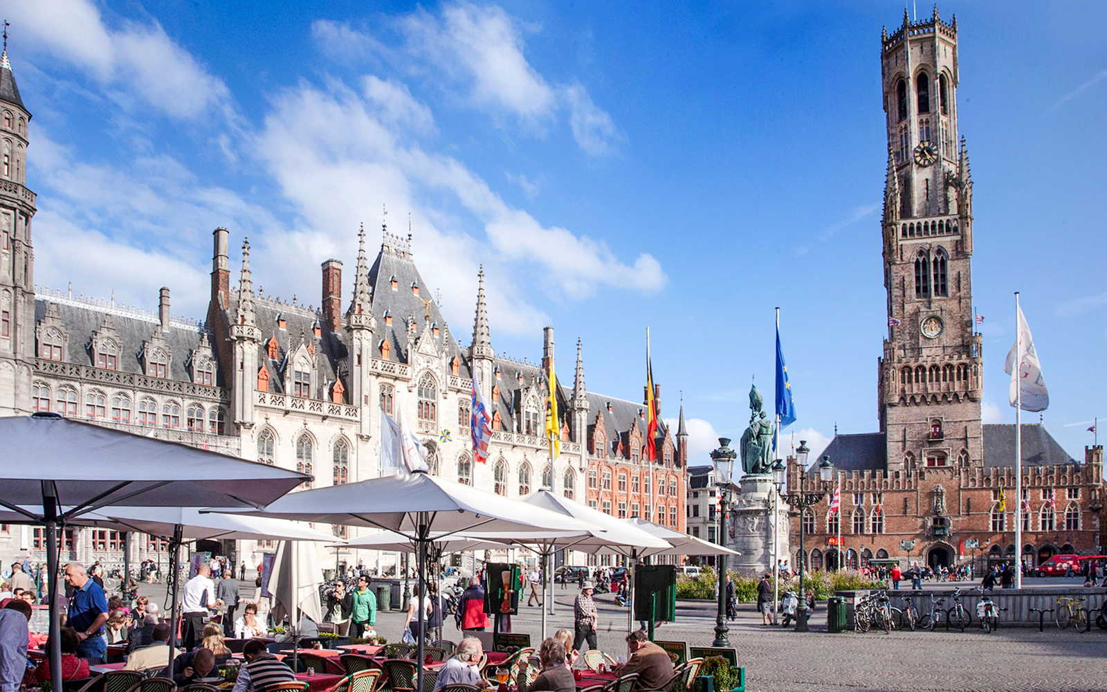 Outdoor cafes and historical buildings at the Markt in Bruges, Belgium, with the Belfry tower.