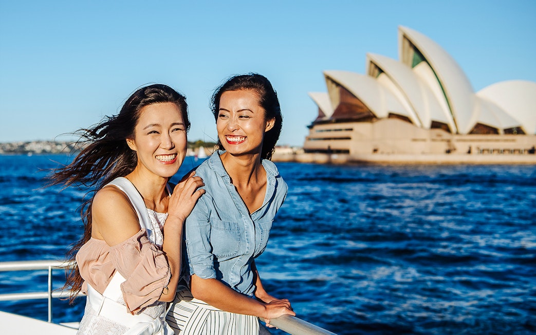 Women smiling on a boat with Sydney Opera House in the background, Sydney Harbour.