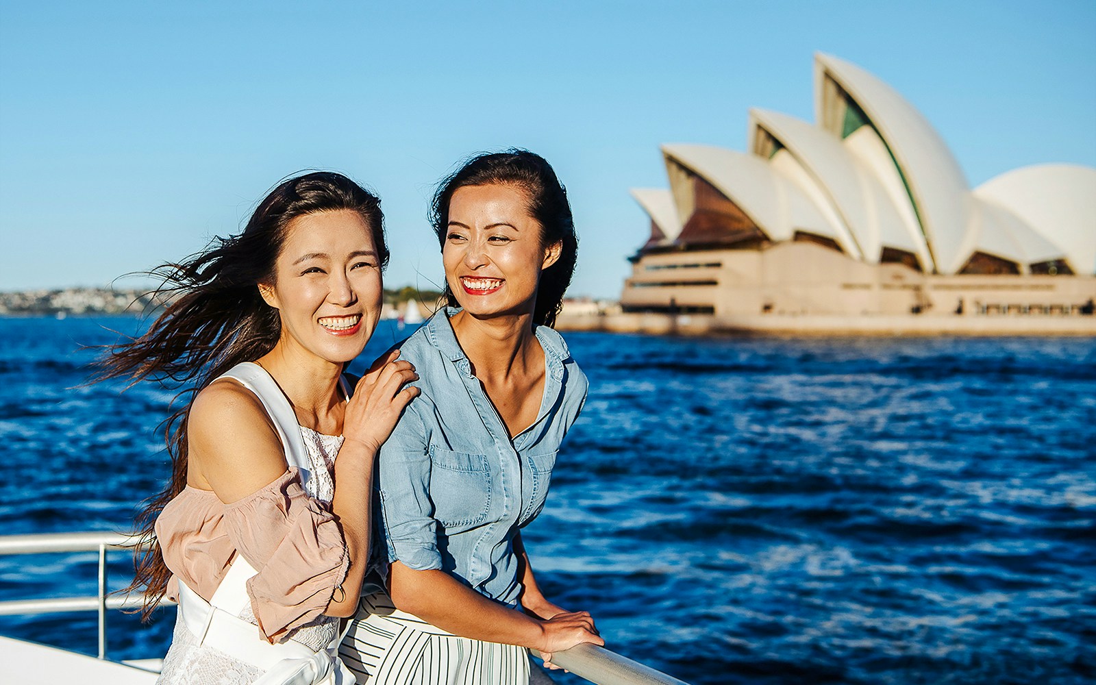 Women enjoying a view of the Sydney Opera House across Sydney Harbour.