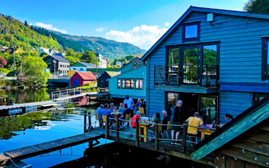 Guests dining on the deck at Hosanger Sea House with scenic waterfront views.