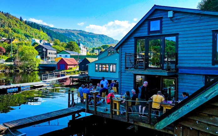 Guests dining on the deck at Hosanger Sea House with scenic waterfront views.
