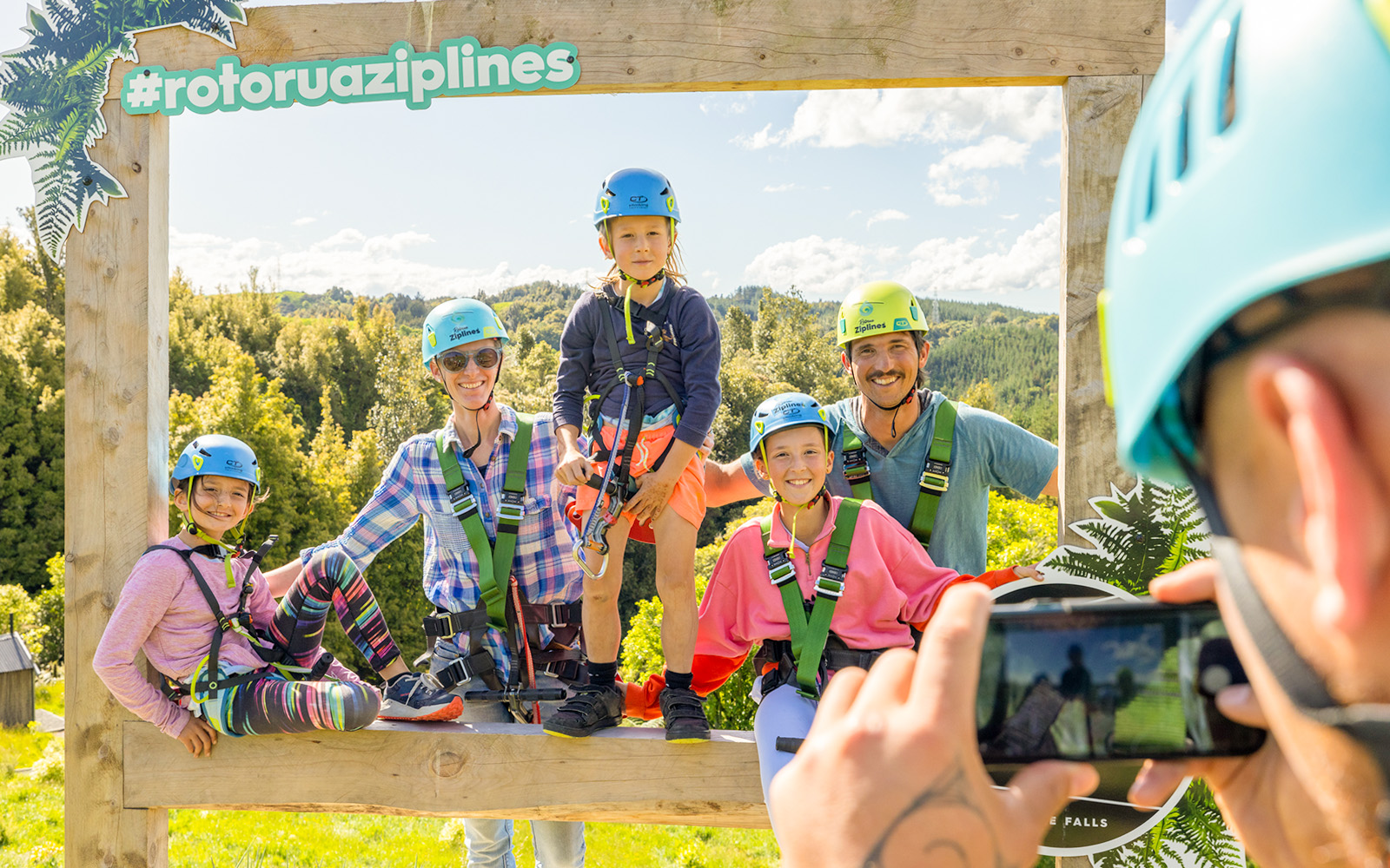Group posing at Rotorua Ziplines with helmets and harnesses, surrounded by lush forest.