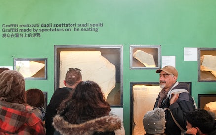 Tour group viewing ancient graffiti at Colosseum exhibit, Rome.