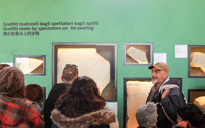 Tour group viewing ancient graffiti at Colosseum exhibit, Rome.