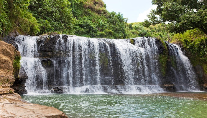 Talofofo Falls Park waterfall cascading over rocks surrounded by lush greenery in Guam.