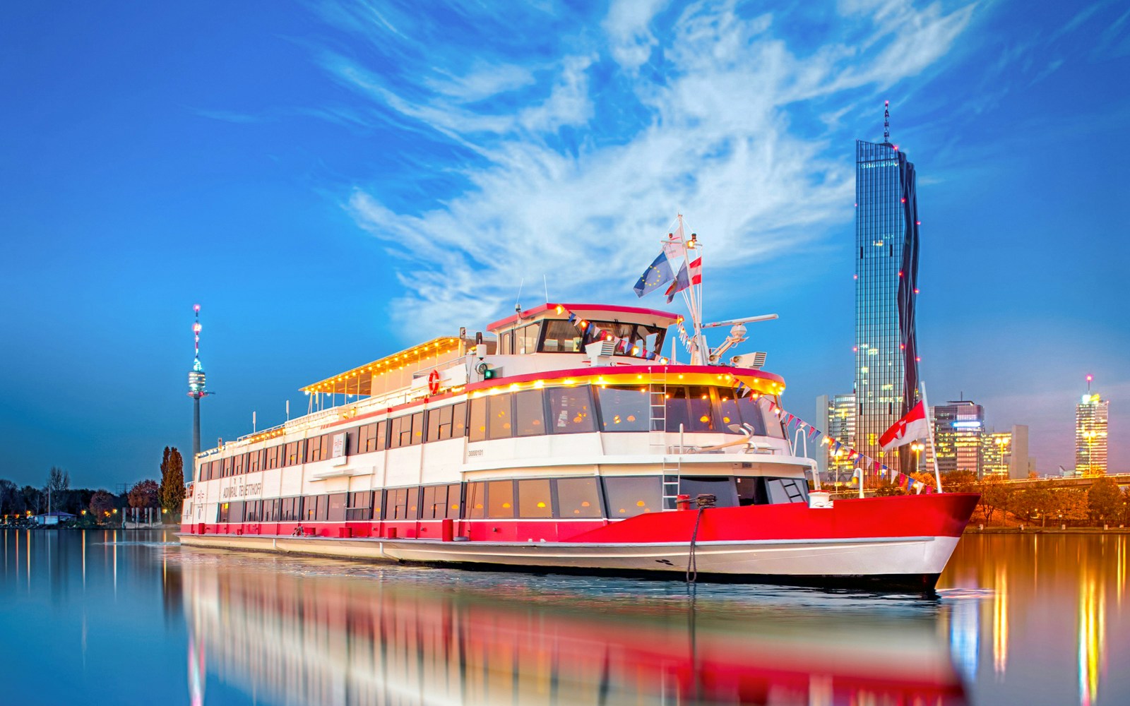 River cruise ship on the Danube River in Vienna, Austria, with city skyline in the background.