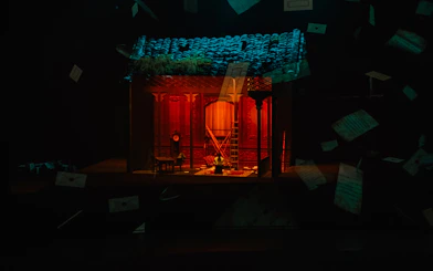 Stage set for "The Legacy of a Generation Show" with red lighting and scattered papers.
