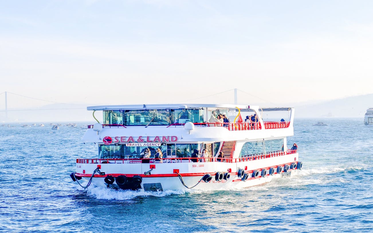 Cruise ship on Bosphorus during sightseeing tour with bridge in background.