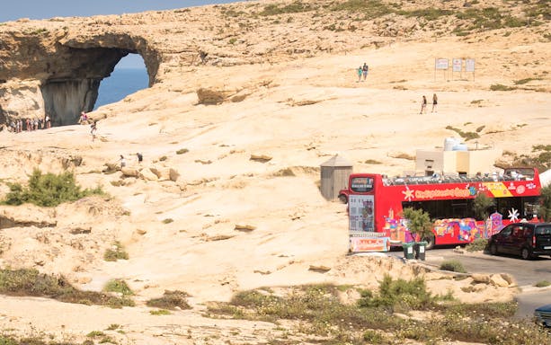 Gozo sightseeing bus near Azure Window rock formation, Malta.