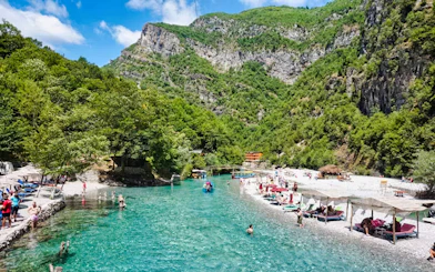 Guests swimming in Shala River surrounded by lush green mountains.