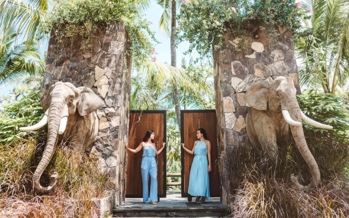 Visitors at the entrance gate of Lombok Wildlife Park, Tanjung, Indonesia, with elephant statues.