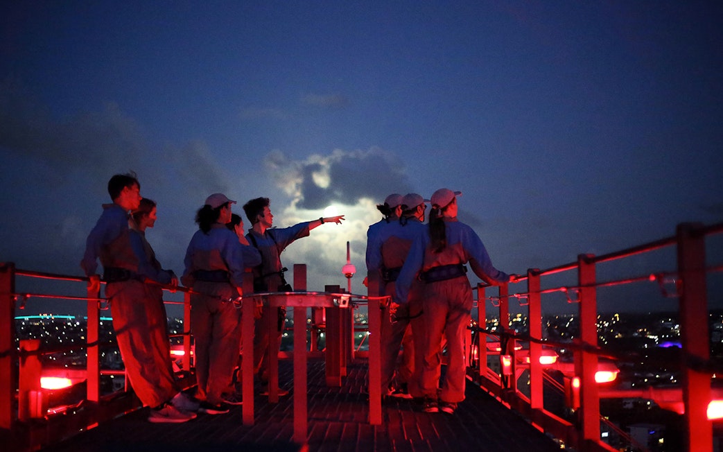 Group climbing Brisbane Story Bridge at twilight, overlooking city lights.