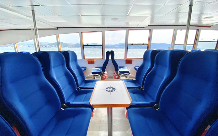 Interior seating area on a Cinque Terre cruise ship with ocean view through windows.