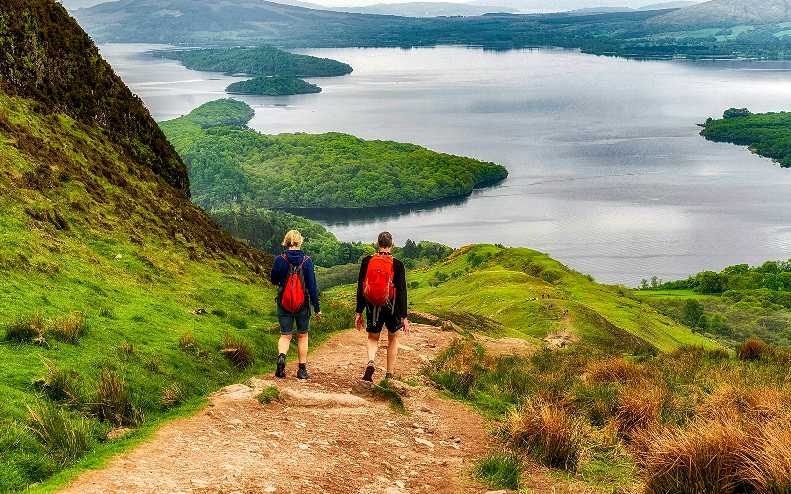Hikers on a trail overlooking a loch in the Isle of Skye, The Highlands.